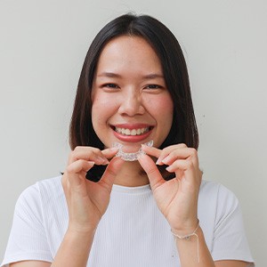 Woman smiling while holding clear aligner