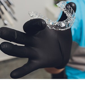 Dentist with black gloves holding clear aligner