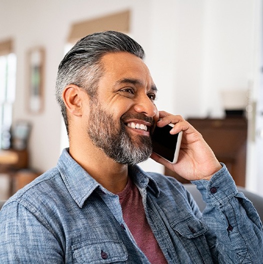 Man smiling while talking on phone at home