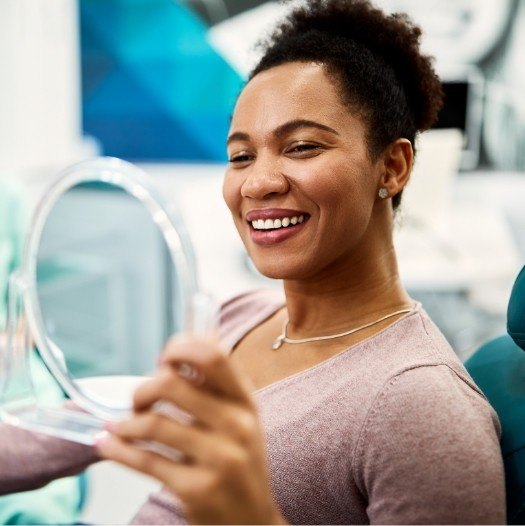 Dental patient admiring her smile in a mirror