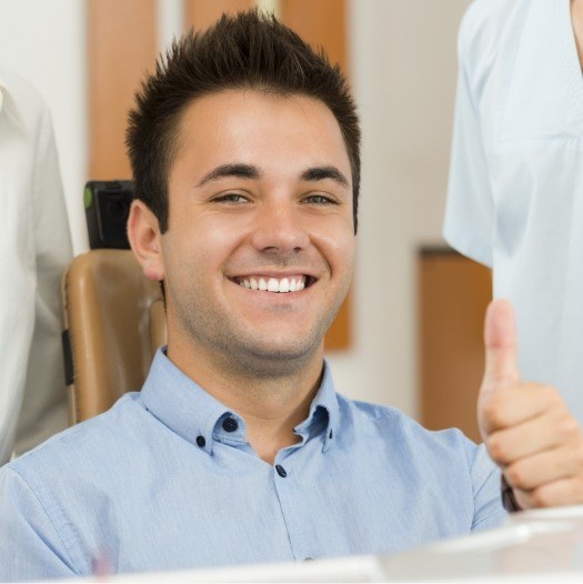 Smiling man in dental chair giving a thumbs up