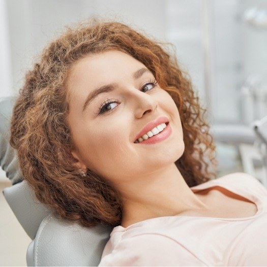 Woman with curly hair grinning in dental chair