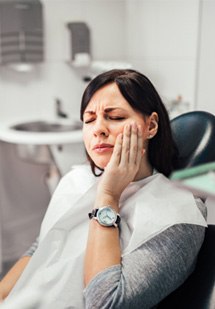 a person holding their cheek due to tooth pain