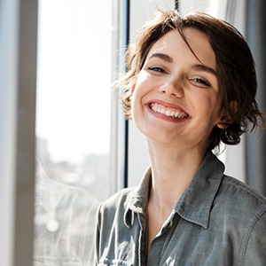 a smiling woman standing in front of a window