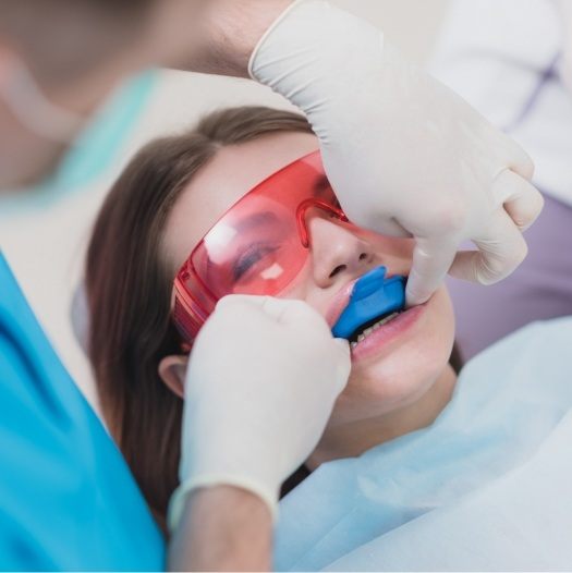 Woman in dental chair with fluoride trays over her teeth