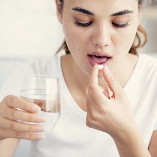 Woman taking a pill with a glass of water