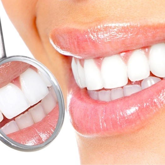 Close up of dental mirror reflecting smile with white teeth