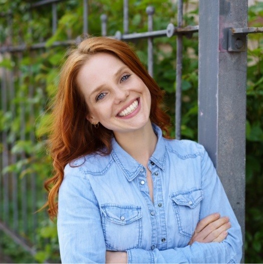 Woman in denim jacket grinning outdoors