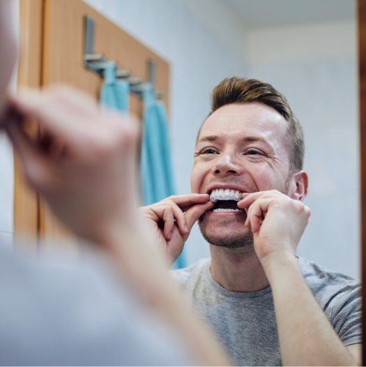 Man placing teeth whitening tray in his mouth