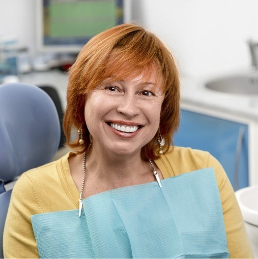 Smiling redheaded woman in dental chair