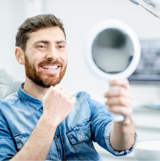 Dental patient looking at his smile in mirror